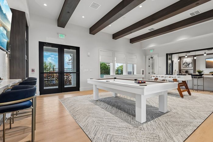 Elegant recreation room featuring a stylish white pool table, modern chairs, and sleek design accents, perfect for entertainment.