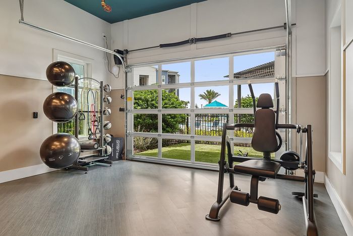 Modern fitness room with gym equipment, large windows, and garden views for an inspiring workout environment.
