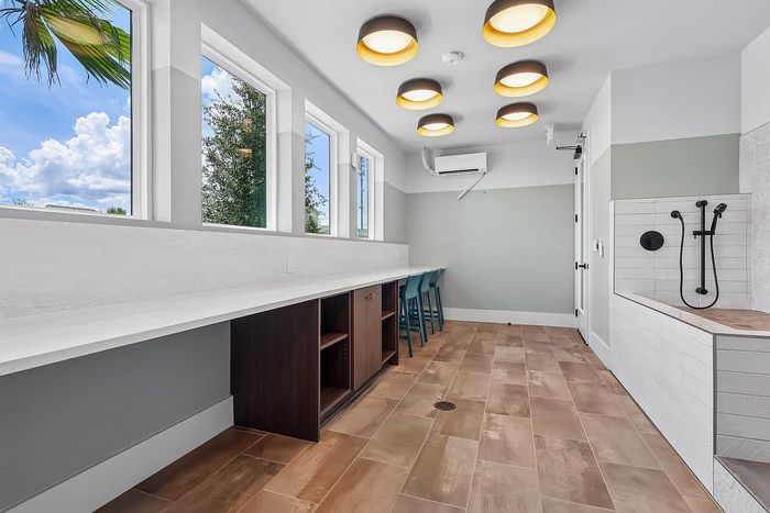 Sunlit modern workspace with large windows, sleek countertops, chic lighting, and elegant tile flooring.