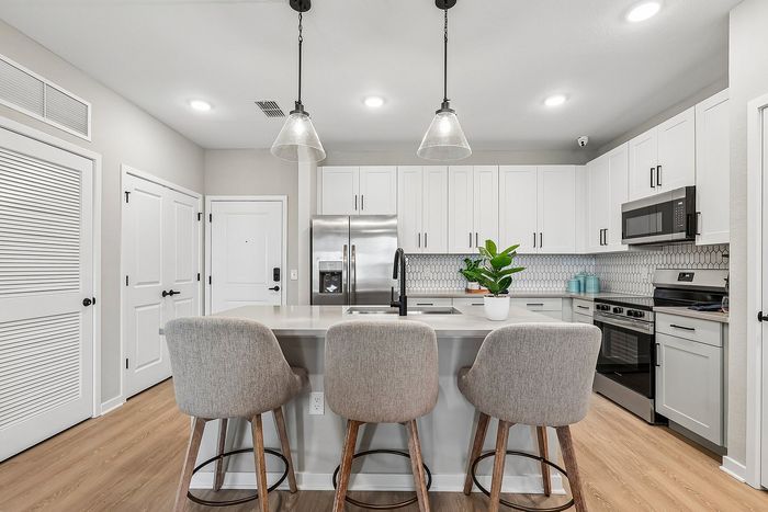 Modern kitchen with sleek white cabinetry, stainless steel appliances, and a stylish island with cozy bar stools.