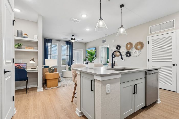 Modern open-concept living space featuring a stylish kitchen island, cozy workspace, and elegant decor with abundant natural light.