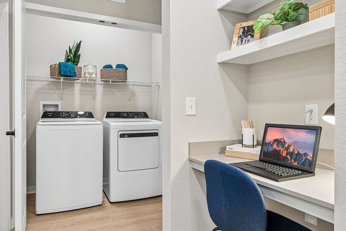 Bright home office setup with a stylish laundry area featuring modern appliances and organized storage solutions.