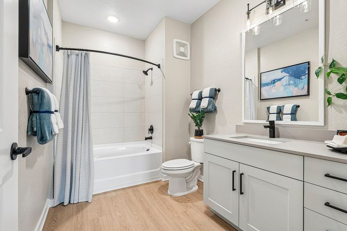 Elegant bathroom with modern fixtures, featuring a spacious bathtub, stylish vanity, and bright ambient lighting.