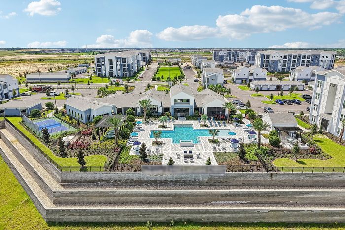 Luxury apartment complex with resort-style amenities, including a grand swimming pool, lush landscaping, and tennis courts set in a vibrant community.