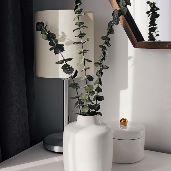 Elegant interior with a modern white vase and fresh greenery, creating a serene and stylish atmosphere.