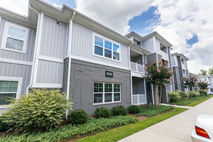 Modern apartment building with stylish gray finishing, lush landscaping, and bright white accents creating an inviting living space.