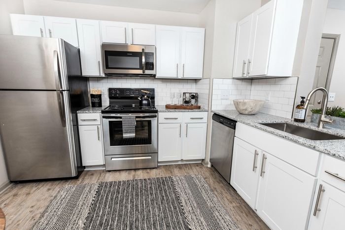 Modern kitchen with sleek stainless steel appliances, white cabinetry, and elegant granite countertops.