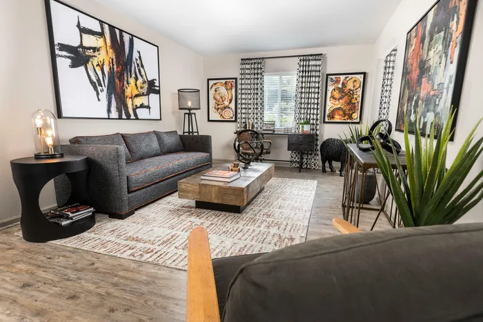Chic living room with modern decor, featuring abstract artwork, stylish grey sofa, and elegant wooden coffee table.