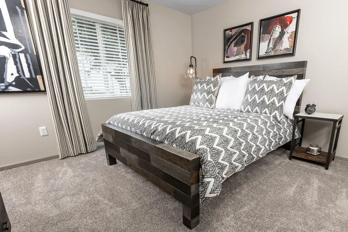 Cozy bedroom with stylish wooden bed, patterned bedding, and modern artwork, perfect for relaxation.