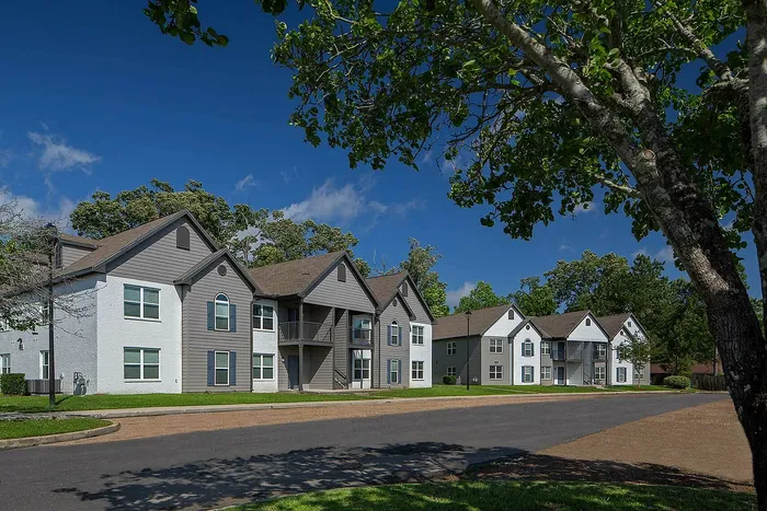 Charming suburban apartment complex surrounded by lush greenery, showcasing modern architecture under a vibrant blue sky.