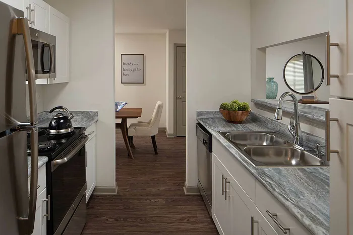 Modern kitchen with sleek appliances and elegant countertops next to a cozy dining area, perfect for gatherings.