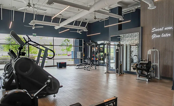 Modern gym with state-of-the-art equipment, large windows, and motivational lighting, offering an inspiring workout environment.