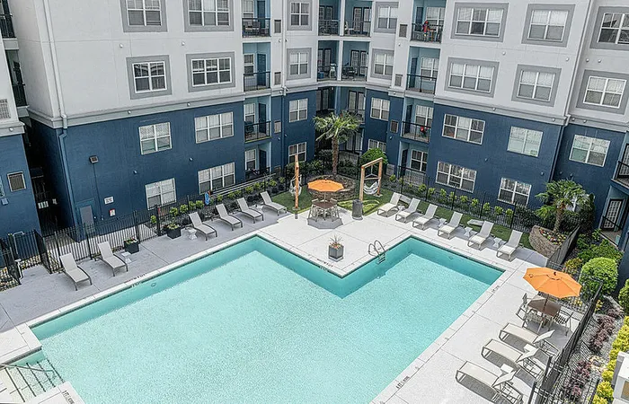 Chic apartment complex with a crystal-clear swimming pool surrounded by stylish loungers and vibrant landscaping.