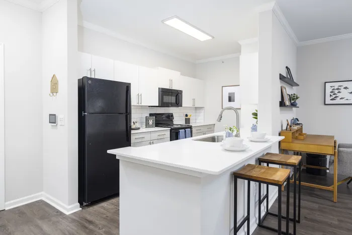 Chic modern kitchen with sleek black appliances, white cabinetry, and a stylish island counter perfect for dining.