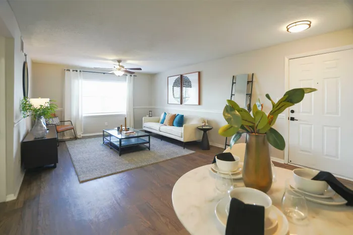 Inviting living room with contemporary decor, featuring a cozy sofa, stylish coffee table, and bright window, accented with elegant details and lush greenery.