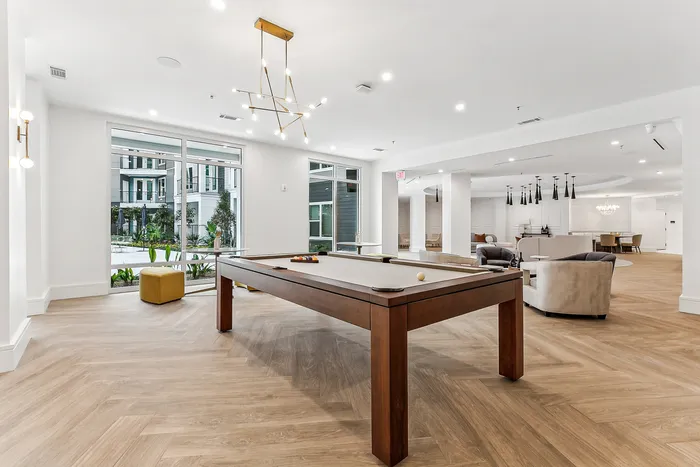 Luxurious lounge with elegant lighting, pool table, and modern decor overlooking lush courtyard.