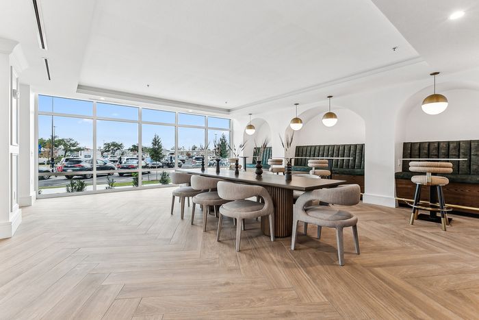 Modern communal dining area with elegant lighting, large windows, and stylish seating, perfect for social gatherings.