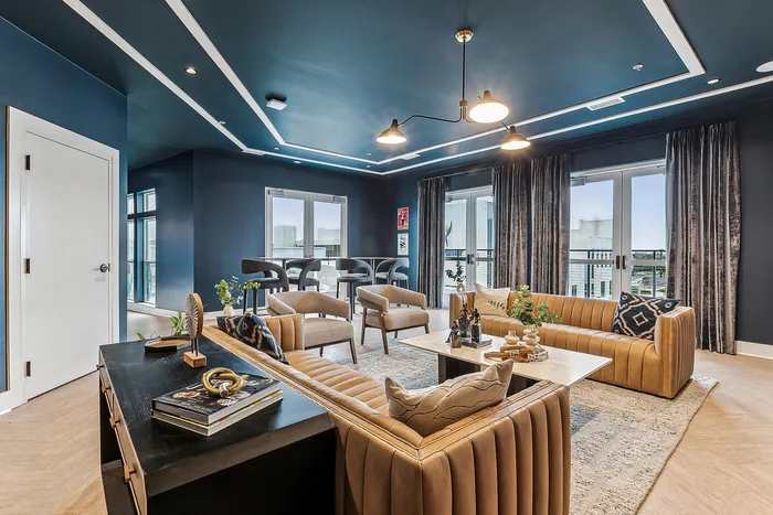 Sophisticated modern living room with sleek blue ceiling, stylish tan sofas, and large windows offering abundant natural light.