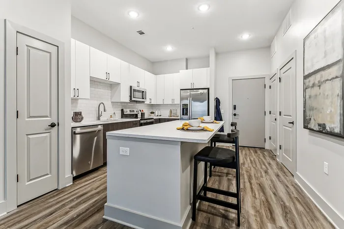 Modern kitchen with sleek white cabinetry, stainless steel appliances, and a spacious island with seating in a luxury apartment.