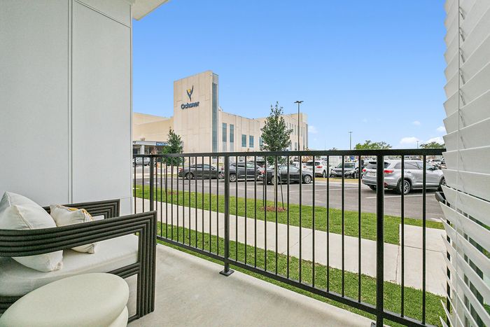 Charming apartment balcony with modern seating and a picturesque view of a bustling campus nearby.