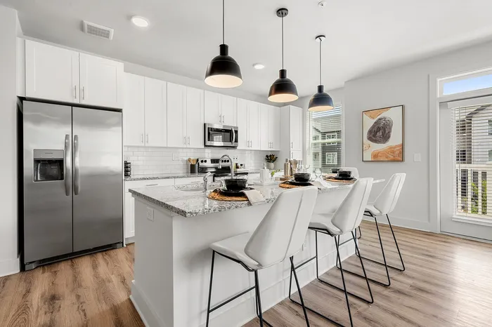Modern kitchen with sleek white cabinetry, stainless steel appliances, and a spacious island with elegant bar seating.