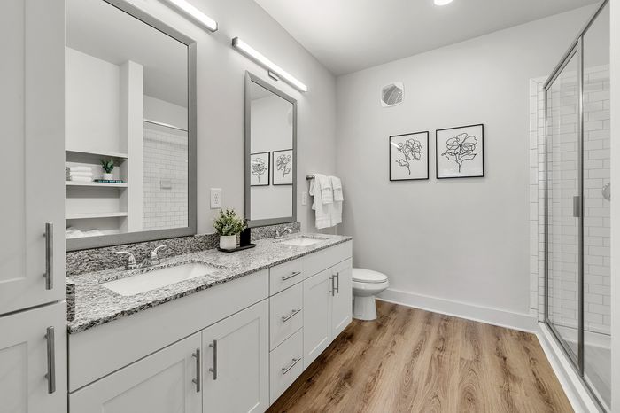 Luxurious bathroom featuring sleek granite countertops, dual sinks, elegant fixtures, and modern artwork for a sophisticated touch.