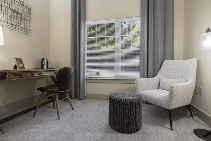 Cozy home office with elegant wooden desk, comfortable upholstered chair, and large window offering natural light.