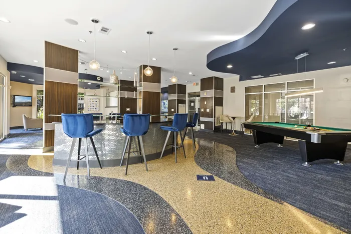 Chic modern lounge with stylish bar seating, pool table, and dynamic floor design, perfect for relaxation and entertainment.