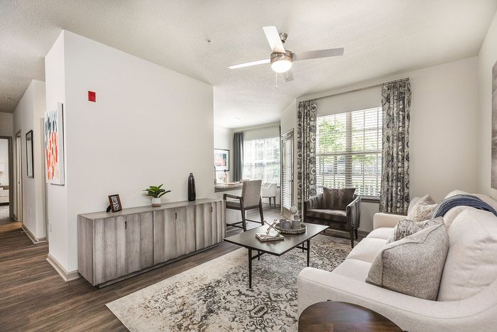 Bright and elegant living room with chic decor, featuring a cozy sofa, stylish armchairs, and large windows allowing natural light to flood the space.