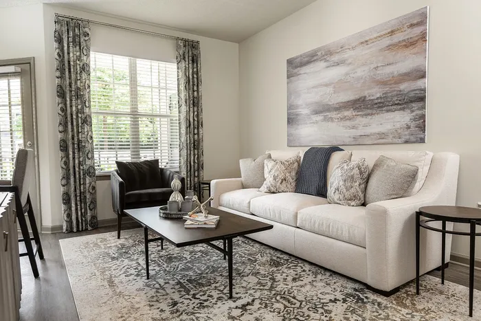 Bright and elegant living room with chic decor, featuring a cozy sofa, stylish armchairs, and large windows allowing natural light to flood the space.