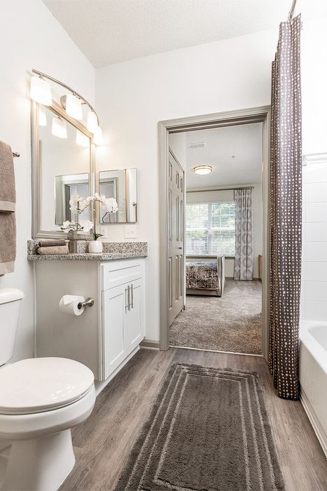 Elegant bathroom with a granite countertop and modern fixtures, leading to a bright and cozy bedroom with large windows.