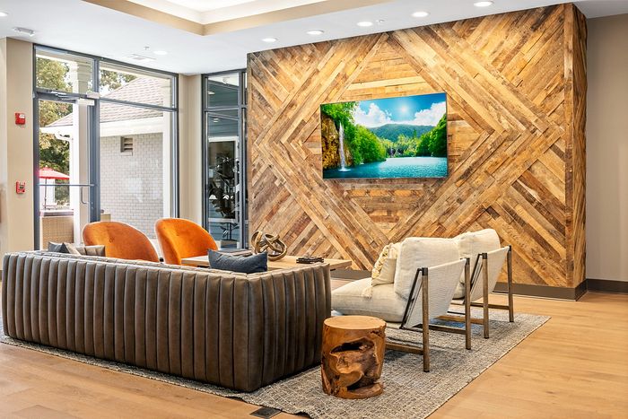 Chic and inviting lounge area with modern seating, rustic wood accent wall, and vibrant artwork.