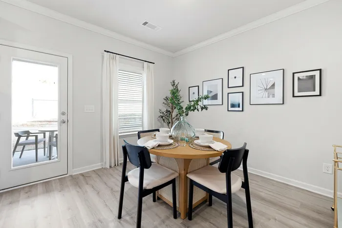 Chic dining area with a stylish round wooden table, elegant tableware, and modern decor, complemented by framed wall art for a sophisticated ambiance.