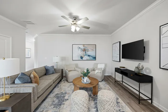 Elegant living room with contemporary decor, featuring a comfortable beige sofa, stylish armchairs, and a sleek TV setup, enhanced by modern art and a decorative round wooden coffee table.
