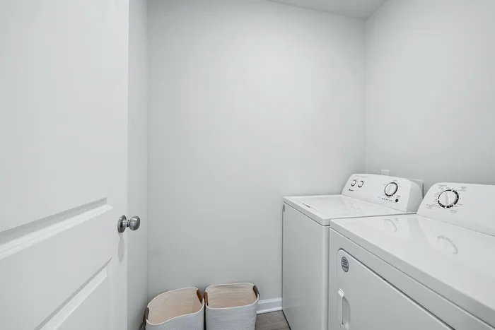 Contemporary laundry room with sleek white washer and dryer combo, complemented by stylish storage baskets. Bright and functional design ready to enhance your home.