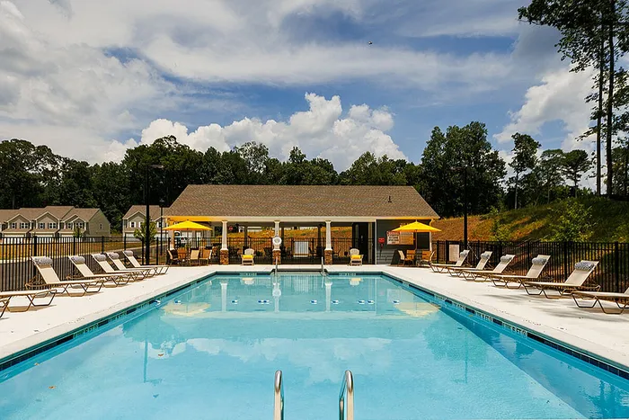 Inviting outdoor swimming pool area with lounge chairs and vibrant yellow umbrellas, perfect for relaxation against a scenic backdrop.