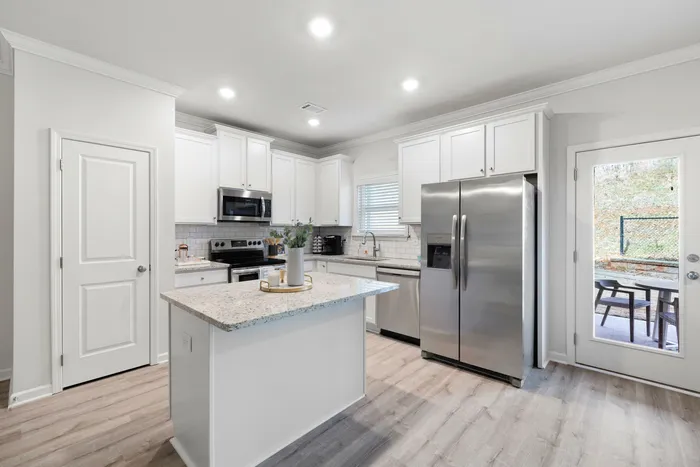 Modern kitchen with sleek stainless steel appliances, elegant white cabinetry, and a stylish granite island countertop, offering a bright and inviting space.