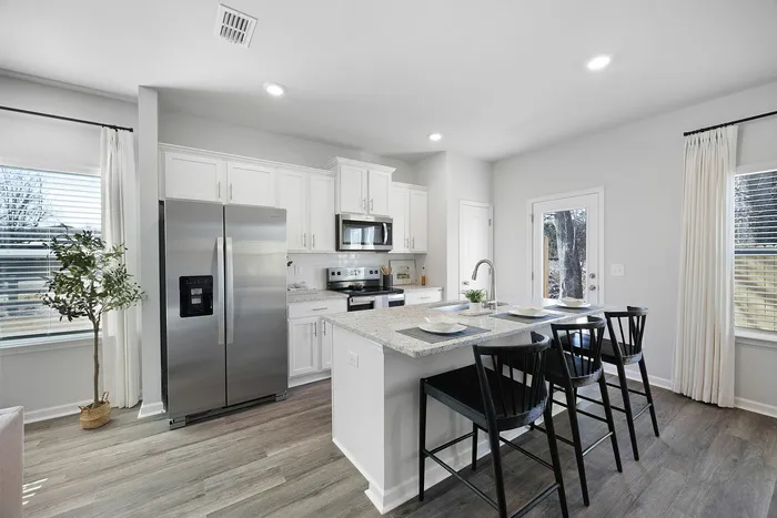 Bright, modern kitchen with sleek white cabinets, stainless steel appliances, and a chic breakfast bar with seating.