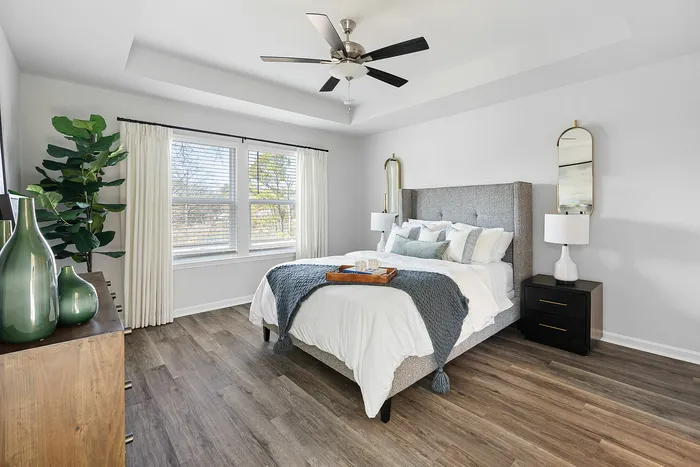Bright and modern bedroom with elegant decor, featuring a cozy bed, stylish mirrors, and large window allowing natural light to fill the space.