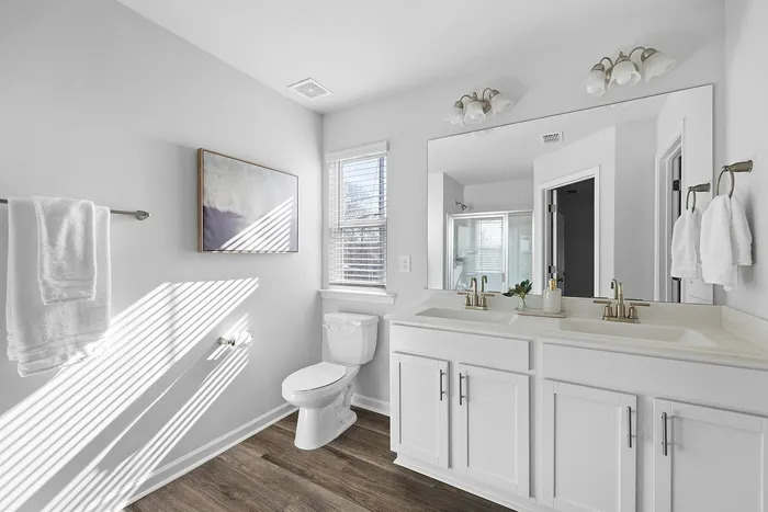 Bright and modern bathroom with sleek dual sinks, elegant fixtures, and abundant natural light.