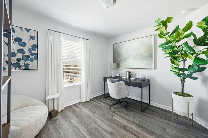 Bright and modern home office with sleek furniture, elegant artwork, and a large window offering natural light.