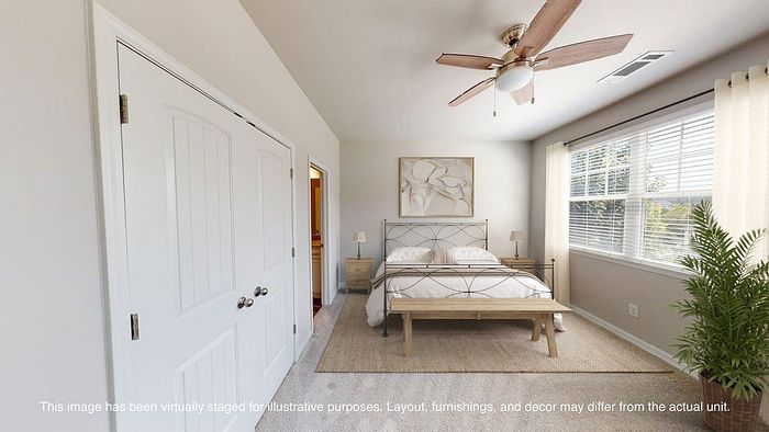 Inviting bedroom with elegant decor, featuring a cozy bed, ceiling fan, and large windows with lush garden views.