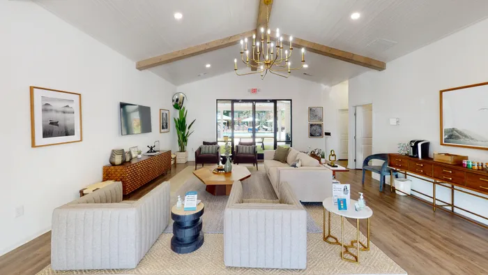 Elegant living room with vaulted ceiling, modern chandelier, and stylish furnishings, ideal for relaxation and entertaining.