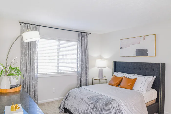 Bright and modern bedroom featuring a plush bed with elegant pillows, stylish artwork, and a cozy ambiance accentuated by soft lighting.