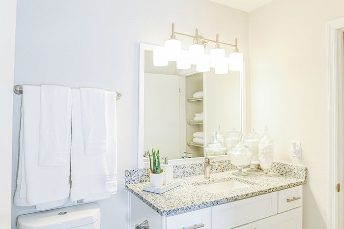 Bright and modern bathroom featuring a sleek granite countertop, elegant lighting, and stylish storage solutions.