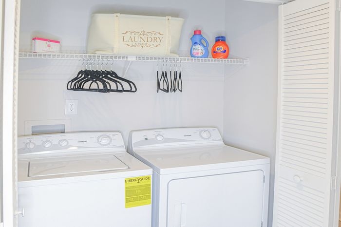 Bright and efficient laundry room featuring modern washer and dryer with ample shelving and storage solutions.