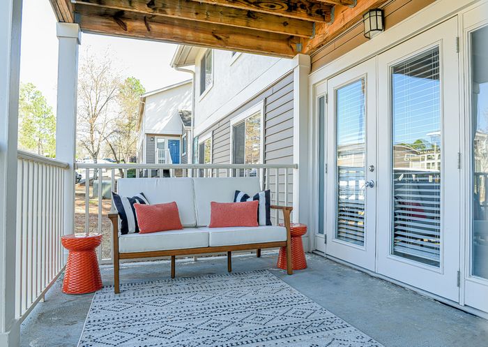Charming balcony with stylish seating, cozy cushions, and natural light through double doors, perfect for relaxation.