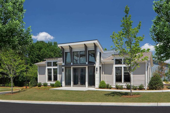 Modern single-story house with large windows, contemporary design, and lush green surroundings.