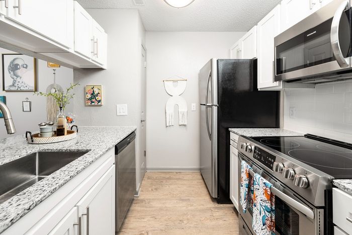 Modern kitchen with sleek granite countertops, stainless steel appliances, and elegant white cabinetry.