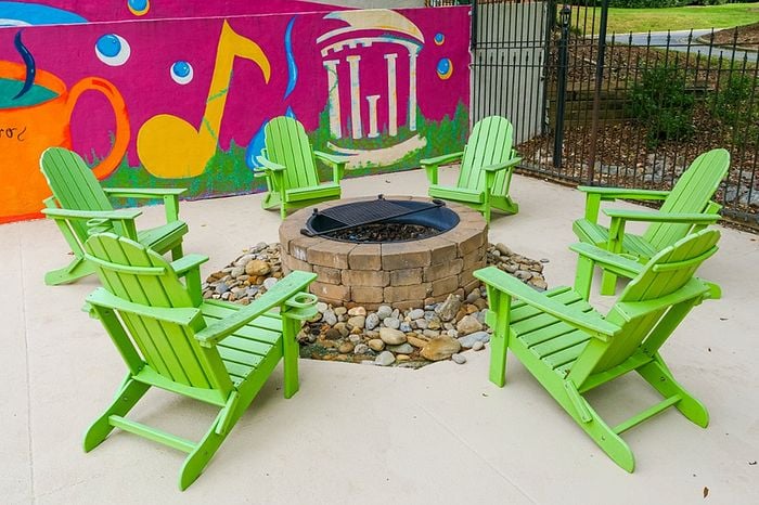 Vibrant outdoor seating area featuring lime green Adirondack chairs around a cozy fire pit, set against a colorful mural backdrop.